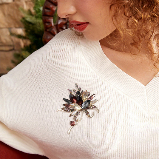 Close-up of a woman wearing a decorative brooch on her white sweater.