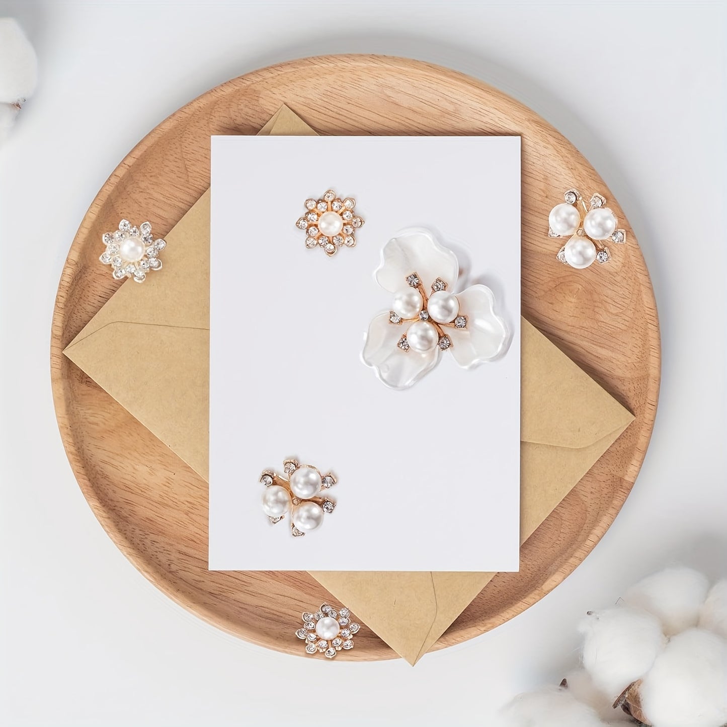 Pearl earrings displayed on a wooden plate with a white card and brown envelope.