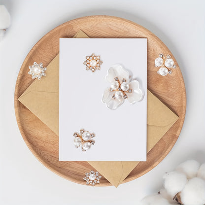 Pearl earrings displayed on a wooden plate with a white card and brown envelope.