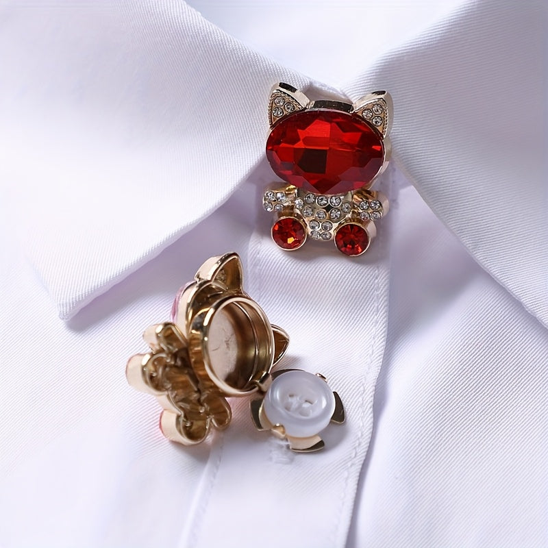 Cat-shaped brooch with red gem and gold accents on a white fabric background