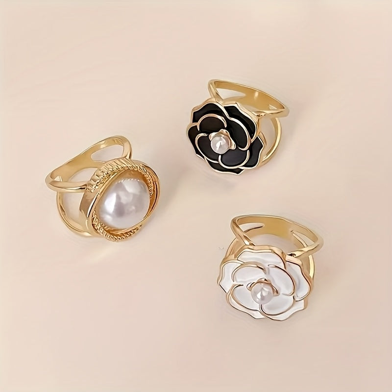 Three gold rings with floral designs and pearls on a beige background