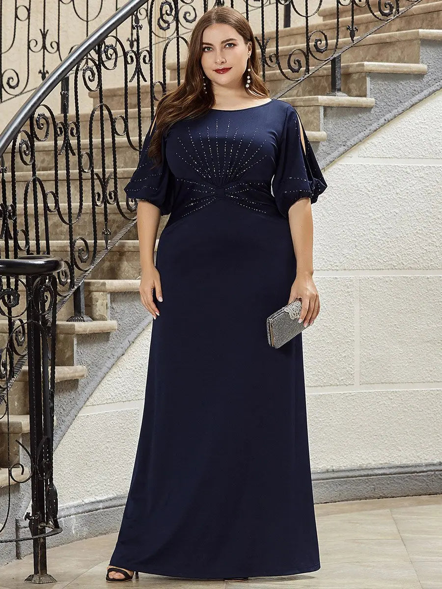 Woman in a navy blue evening gown standing on a staircase.