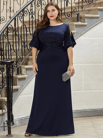 Woman in a navy blue evening gown standing on a staircase.