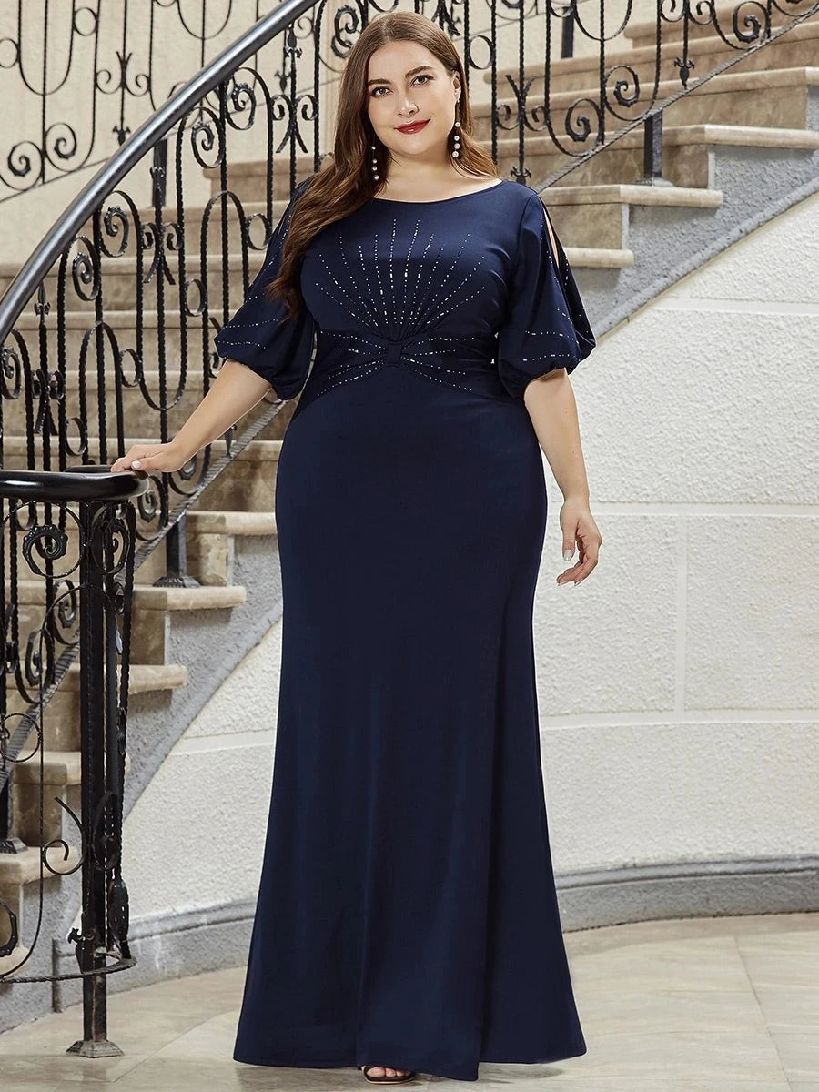 Woman in a navy blue evening gown standing on a staircase.