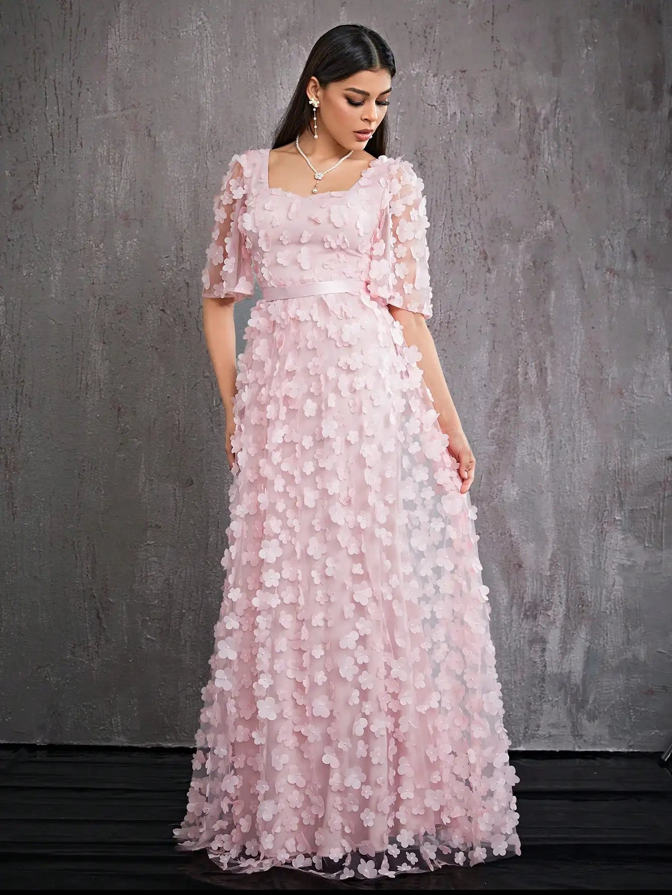 Woman wearing a pink floral dress against a gray background