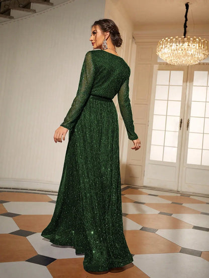 Woman wearing a green evening gown in an elegant room with chandelier.