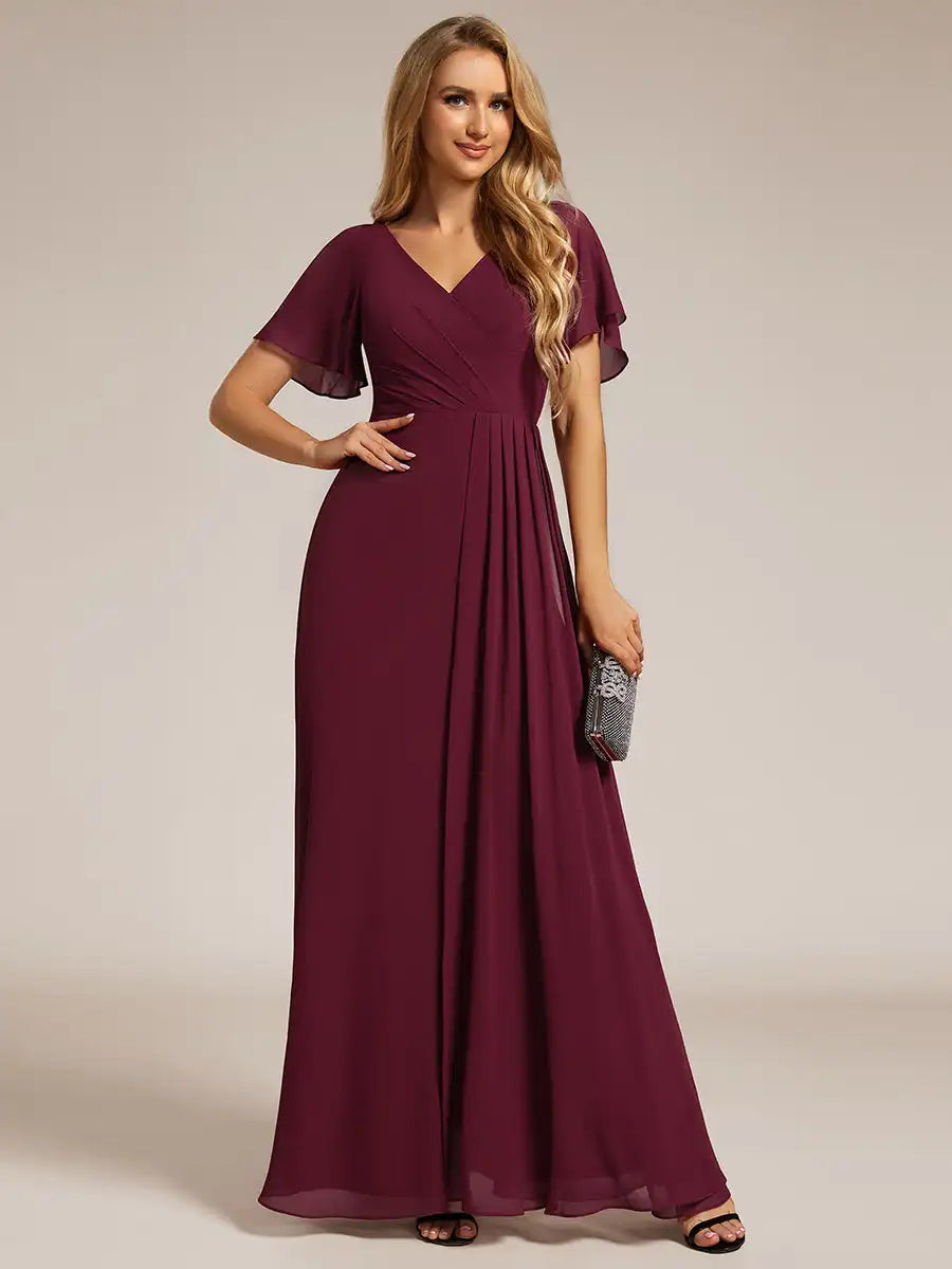 Woman wearing a burgundy evening gown on a plain background