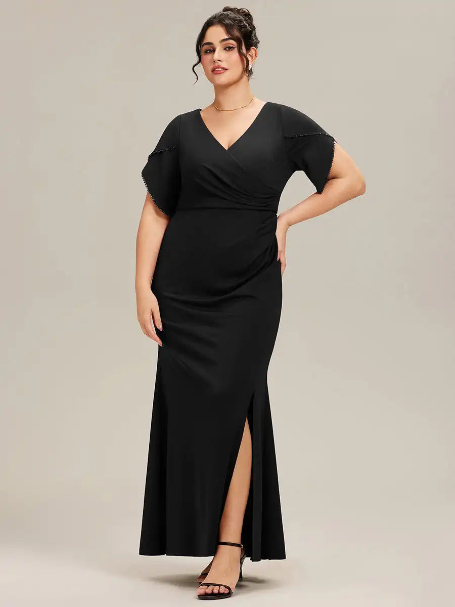 Woman wearing a black dress with a slit on a plain background