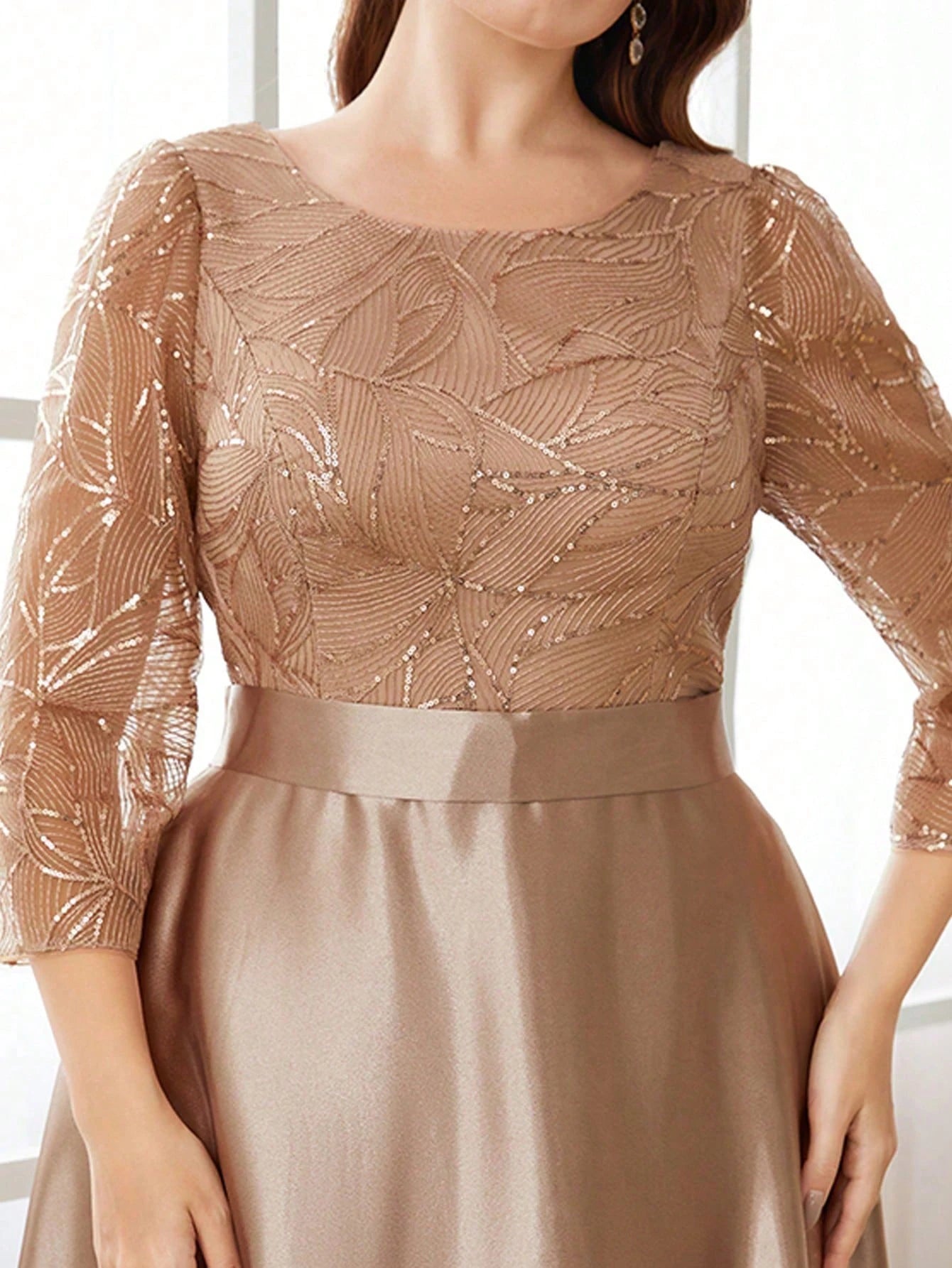 Close-up of a person wearing a beige dress with a patterned top and plain skirt.