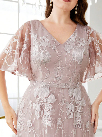 Woman wearing a light pink lace dress with a blurred background