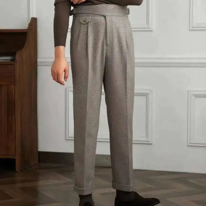 Person wearing gray pants standing in a room with wooden furniture and white walls.