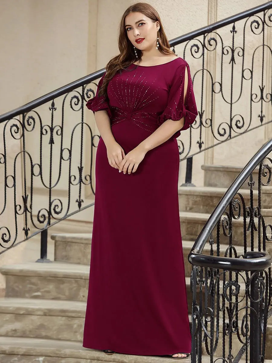 Woman in a burgundy evening gown standing on a staircase with decorative railings.
