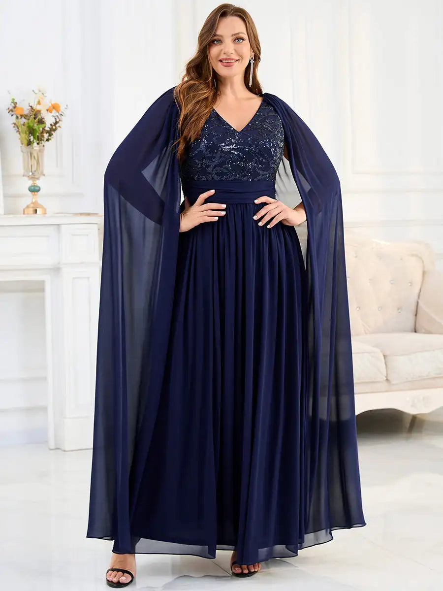 Woman wearing a long navy blue dress with a sheer overlay in a bright room.
