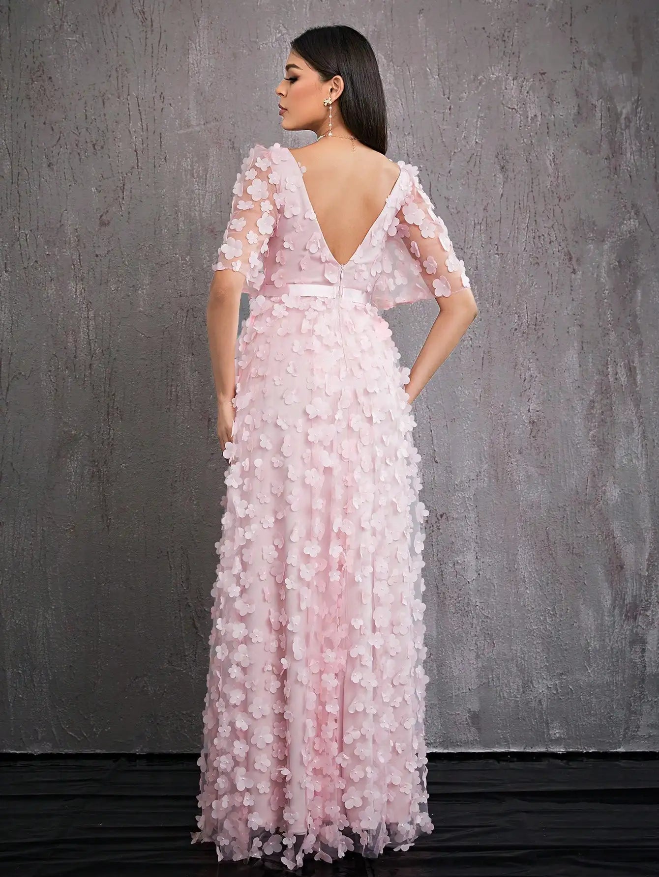 Woman wearing a pink floral evening gown against a gray background