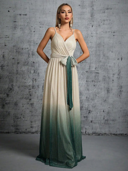 Woman wearing a long, gradient dress with a white top and green skirt against a gray concrete wall.