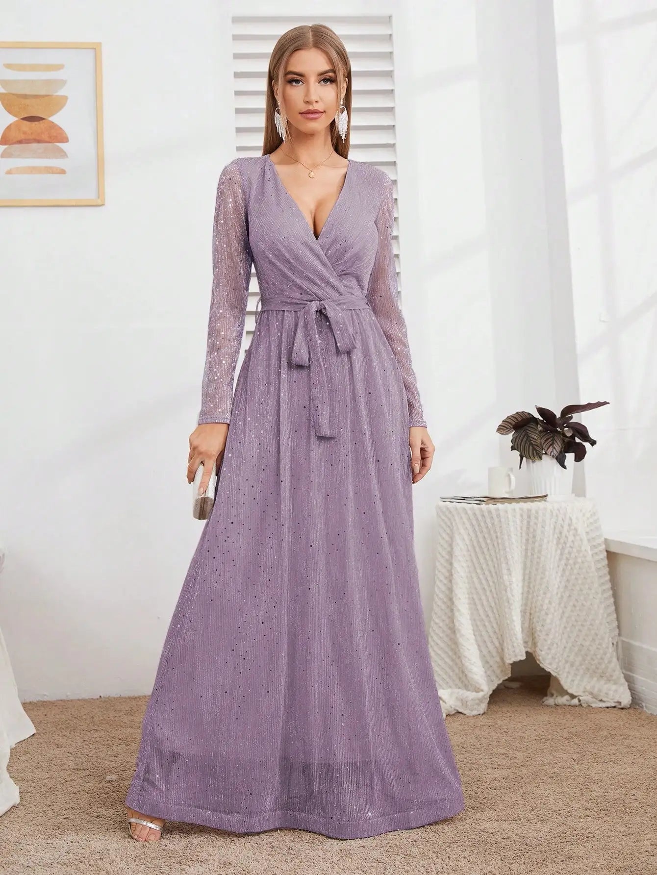 Woman wearing a long purple dress in a room with a table and plant.