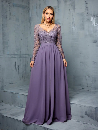 Woman wearing a long purple dress with lace sleeves against a gray concrete wall.