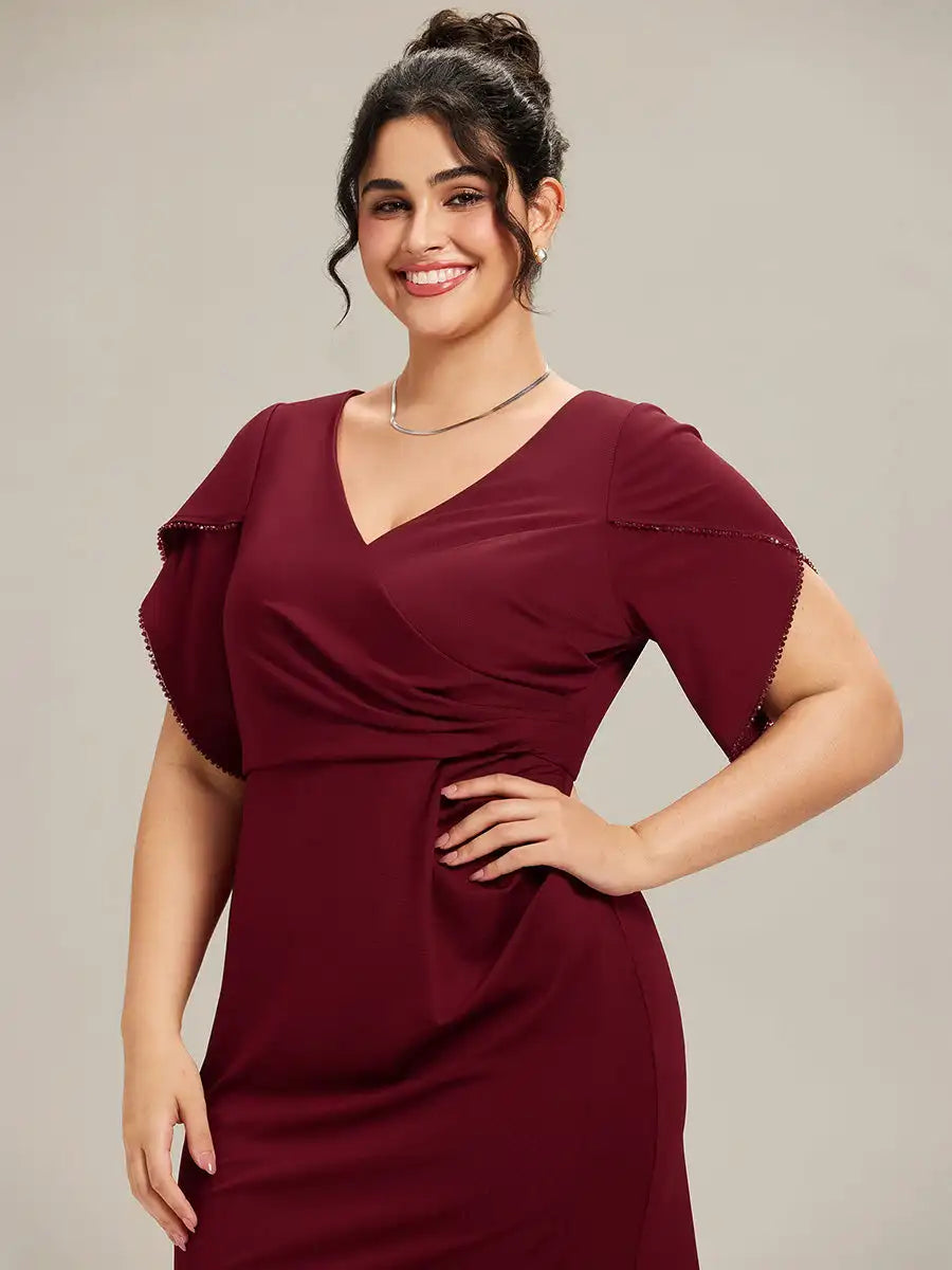 Woman wearing a burgundy dress with ruffled sleeves against a neutral background