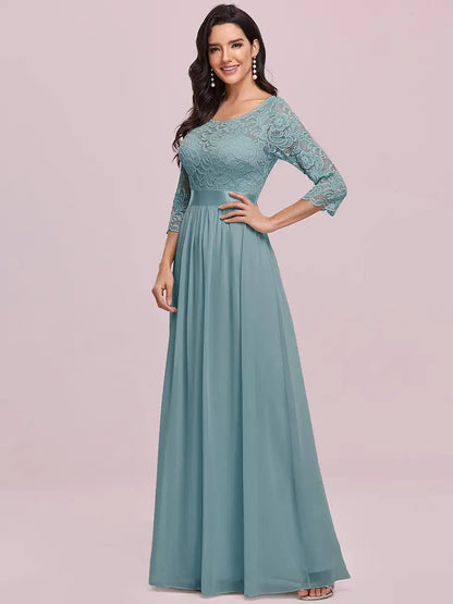 Woman wearing a teal lace dress with a plain background