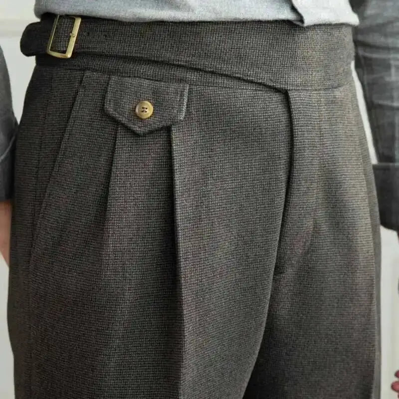 Close-up of gray pleated pants with a button on a plain background