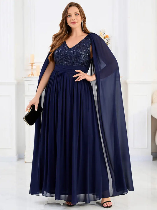 Woman wearing a navy blue evening gown with a sheer overlay in an elegant indoor setting.