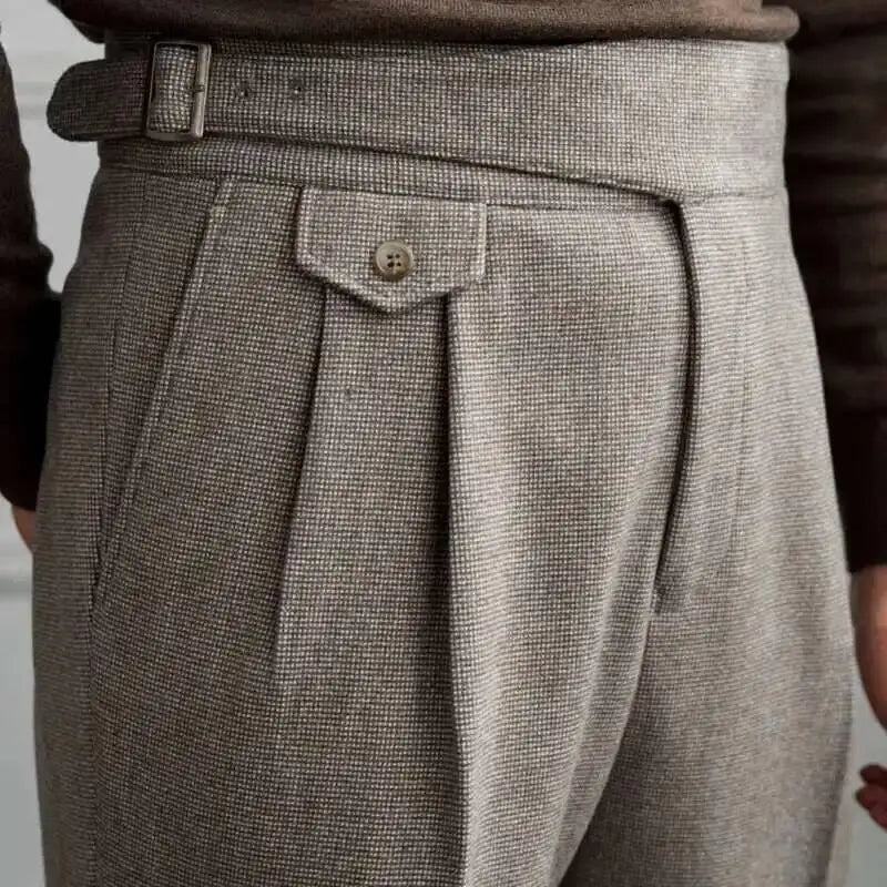 Close-up of a person wearing gray pleated pants with a belt and button.