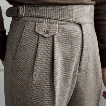Close-up of a person wearing gray pleated pants with a belt and button.