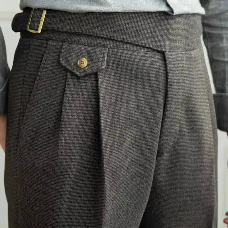 Close-up of gray pleated pants with a button on a plain background