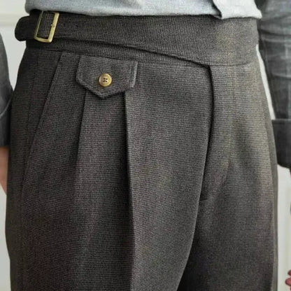 Close-up of gray pleated pants with a button on a plain background