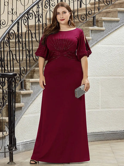 Woman in a burgundy evening gown standing on a staircase.