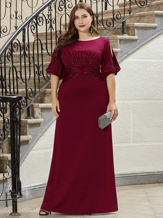 Woman in a burgundy evening gown standing on a staircase.