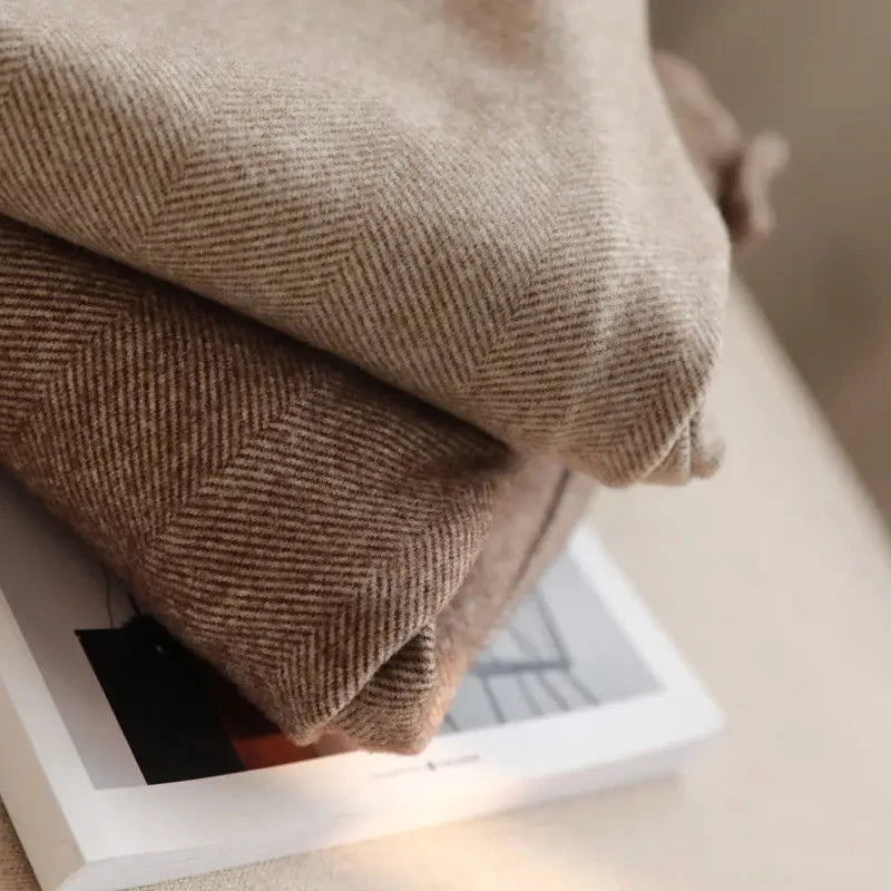 Folded brown herringbone fabric on a white surface with a blurred background