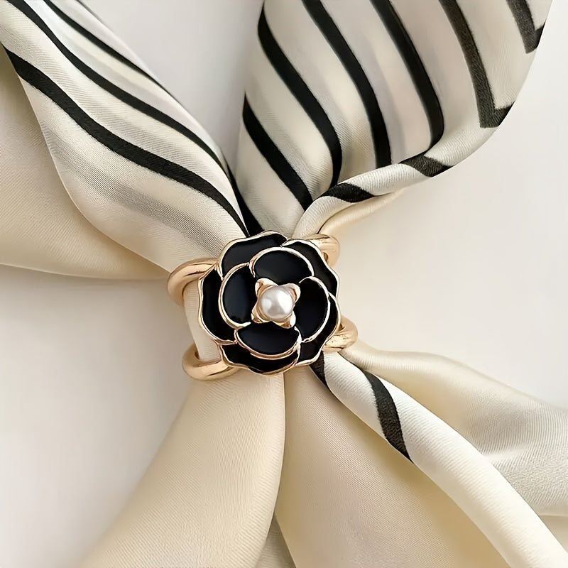 Black and gold flower-shaped brooch on a striped fabric background