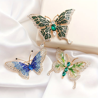 Three butterfly-shaped brooches with gemstone details on a white fabric background