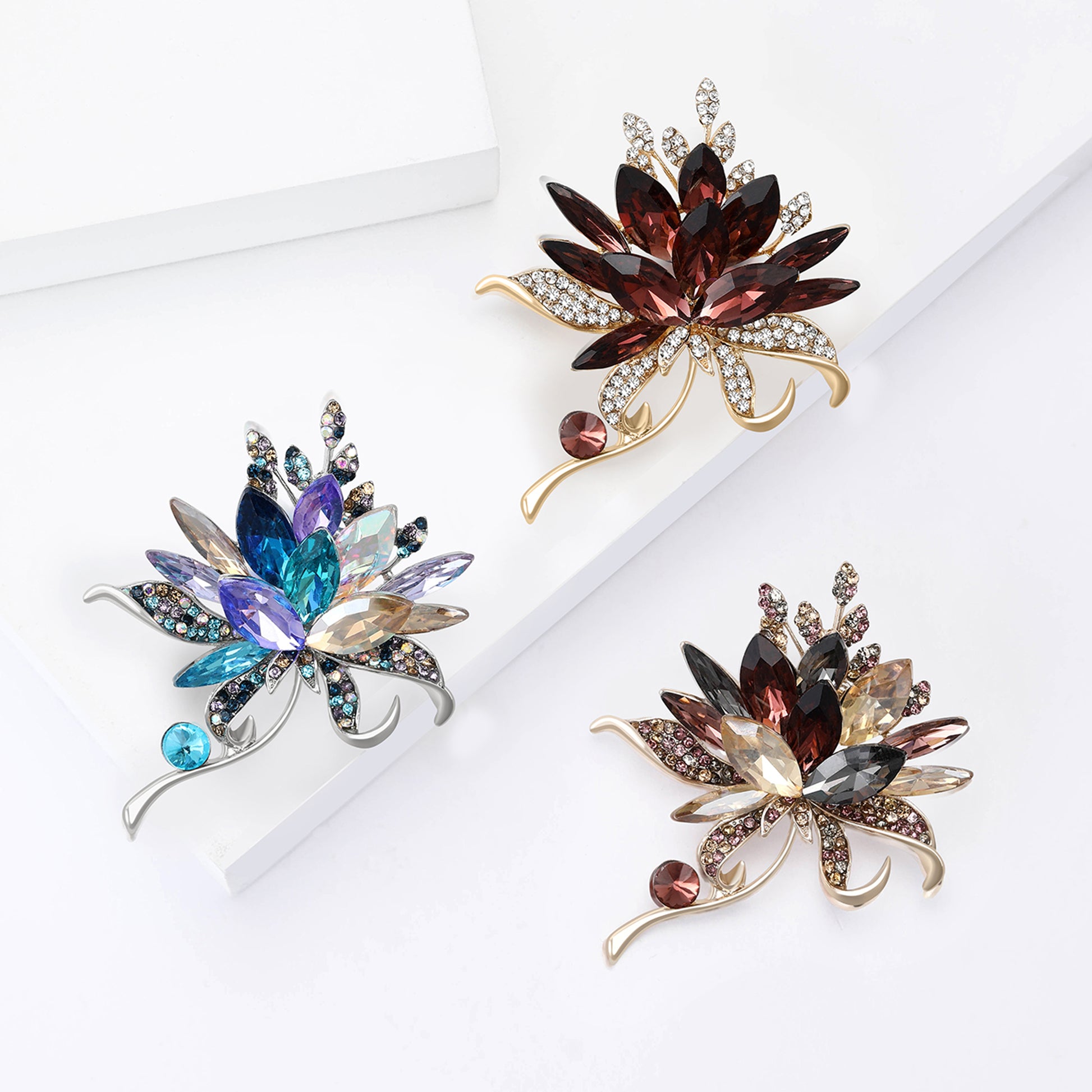 Three ornate brooches with gemstones on a white background